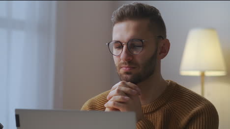 young-man-with-glasses-is-listening-and-viewing-lecture-or-speech-of-participant-of-online-meeting-sitting-in-home-office-distant-communication-and-self-education